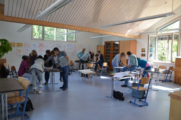 Teilnehmende eines Schulbauworkshops stehen in Gruppen zusammen
